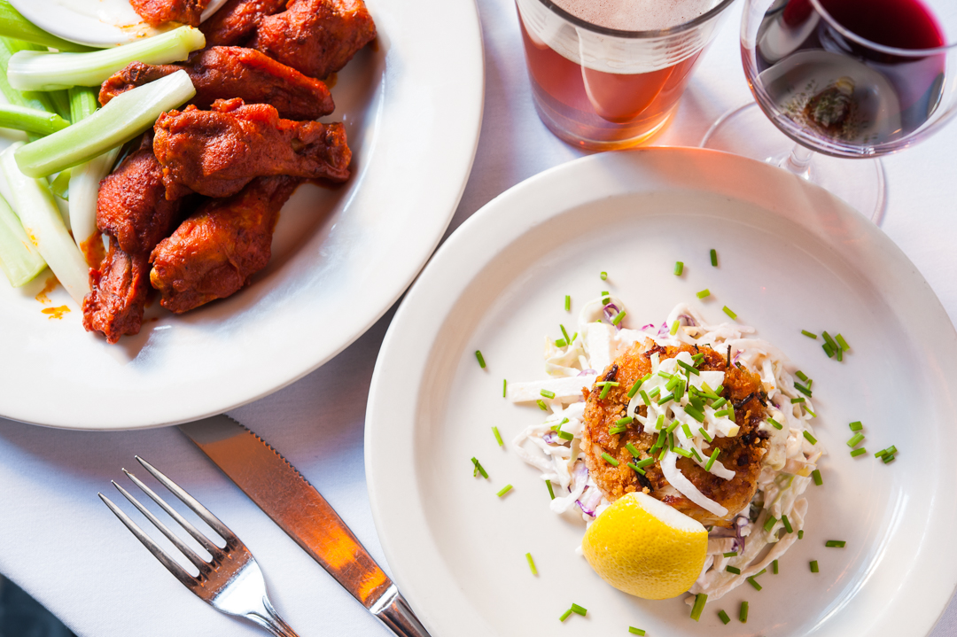 Buffalo Wings, a crab cake with lemon, a draft beer and glass of wine at Joe Allen NYC.